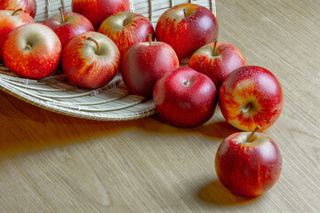 Red apples on a wooden surface in woven basket arrangement