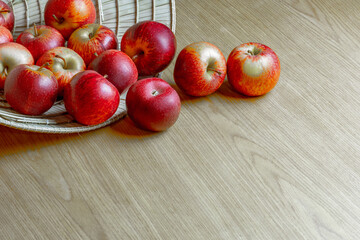 Fresh red apples in a basket on wooden surface