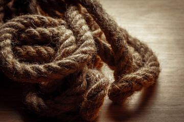Heavy coiled rope on wooden surface with textured fibers and rustic appearance