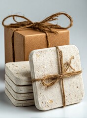 Stack of marble coasters tied with twine, next to a small wrapped kraft paper gift box. Simple, rustic aesthetic on a white surface