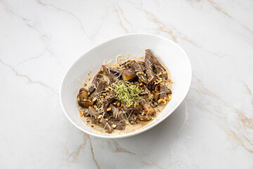 Gourmet beef tongue with creamy sauce, mushrooms and sprouts on marble background