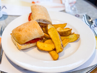 Sandwich with potato wedges served on white plate. Nutrition, refreshment, and lifestyle moments in restaurant and cafe dining.