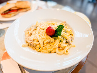 Plate of pasta with parmesan, mushroom, and cherry tomato garnish. Cuisine, nutrition, and lifestyle moments in restaurant dining culture.