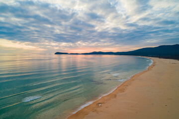 Beautiful coastal sunset with soft waves and serene landscape captured in the evening sky