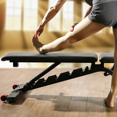 Woman exercising on a training bench in the gym, blurred fitness interior in the background, concept of sport, fitness, and maintaining a healthy lifestyle.