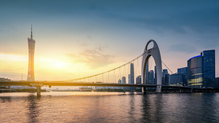 Naklejka premium Beautiful sunset view of modern bridge and skyscrapers by the river