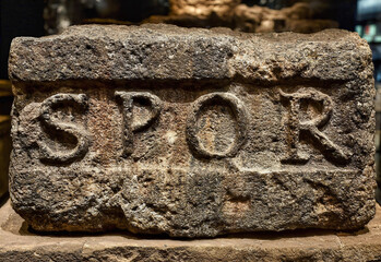 The ancient Roman inscription SPQR is engraved on a stone block worn down by time.