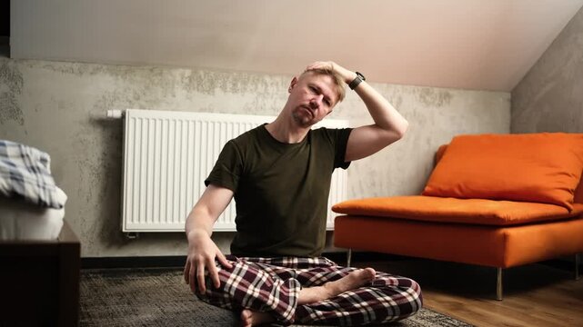 Young Man Stretching Neck While Sitting In Yoga Pose On A Floor At Home