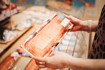 Person holding a package of fresh salmon in a supermarket