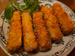 Chả Giò Hải Sản (Seafood Spring Rolls) on a blue-and-white patterned plate, garnished with fresh mint leaves.
