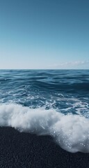 Fototapeta premium Ocean waves lapping at a dark pebble shore under a clear sky