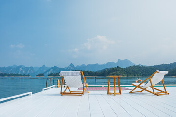 wooden beach chair and coffee table on white raft and swimming pool at waterfront of the open water...