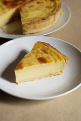 Custard Tart Slice on White Plate with Whole Tart in Background