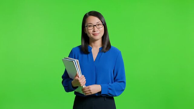 Asian woman presenting with books against green screen background for video editing - Powered by Adobe