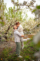 happy couple of adults on a walk in the spring park. family leisure. husband and wife walking in nature