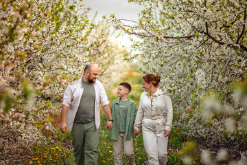 Happy family mom dad and teenager boy having fun on a spring walk in a blooming park