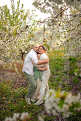 Happy family mom dad and teenager boy having fun on a spring walk in a blooming park
