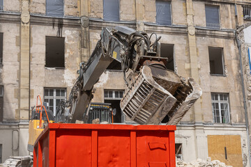 Un engin de destruction avec des pinces en train de prendre des gravats.