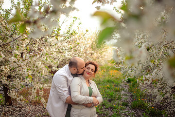 happy couple of adults on a walk in the spring park. family leisure. husband and wife walking in nature