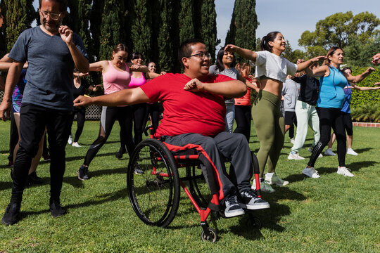 Large Group of Latin sporty multi age people and disabled man in wheelchair in Zumba class outdoors in a public park in Mexico Latin America. Diverse group in social inclusion concept