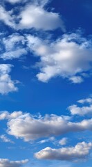 A serene vertical shot of a bright blue sky dotted with fluffy white cumulus clouds, transitioning from light to darker hues overhead
