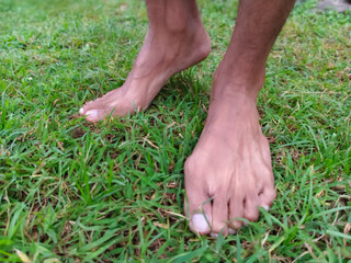 Bare feet of a person on green grass, close-up, low-angle shot. Man's feet standing on a lawn outdoors. A pair of feet on fresh green grass