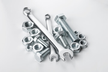 Many metal wrenches, bolts and nuts on white background