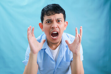 Expressive Portrait of a Male in a Light Blue Shirt Conveying Intense Emotion Against a Soft Blue...