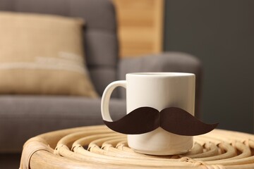 Happy Father's Day. Cup with paper moustache on coffee table indoors, closeup. Space for text