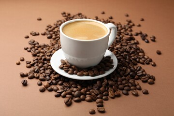Cup of hot coffee and beans on brown background, closeup