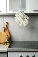 Oven glove and potholder hanging on handle of cabinet in kitchen