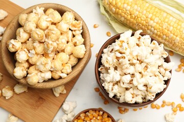 Tasty popcorn and corn kernels on white table, flat lay