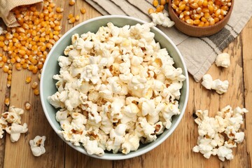 Tasty popcorn and corn kernels on wooden table, flat lay
