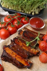Roasted beef ribs with microgreens, tomatoes and sauce on table, closeup