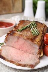 Delicious baked beef meat, tomatoes, rosemary and sauce on table, closeup