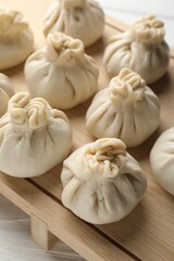 Uncooked khinkalis (dumplings) on white wooden table, closeup