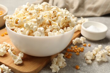 Tasty popcorn and corn kernels on light grey table, closeup