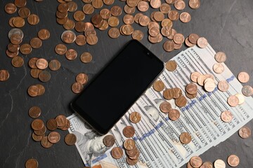 Smartphone, dollars and coins on black table, flat lay