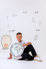 Thoughtful schoolboy in uniform sitting on wooden stool, student portrait with science and math formulas on white background, education and learning concept