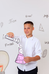 Thoughtful schoolboy in uniform sitting on wooden stool, student portrait with science and math formulas on white background, education and learning concept