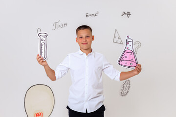 Thoughtful schoolboy in uniform sitting on wooden stool, student portrait with science and math formulas on white background, education and learning concept