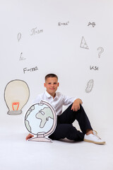 Thoughtful schoolboy in uniform sitting on wooden stool, student portrait with science and math formulas on white background, education and learning concept