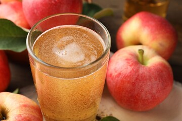 Delicious cider in glass and apples on table, closeup