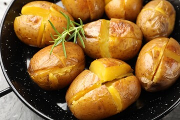 Tasty baked potatoes with rosemary served on light grey table, closeup