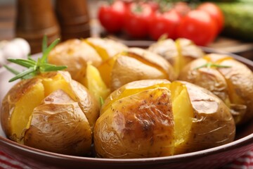 Tasty baked potatoes with rosemary served on table, closeup