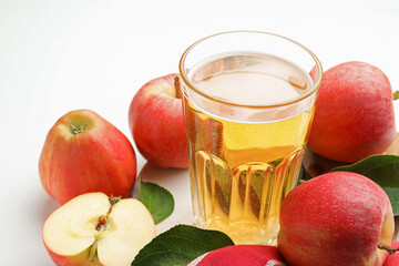 Fresh cider in glass and apples on white table, closeup