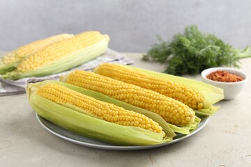 Tasty boiled corncobs on light table, closeup