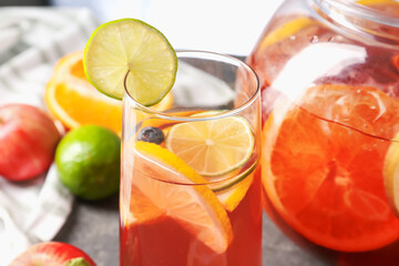 Punch and fresh fruits on grey table, closeup. Refreshing drink