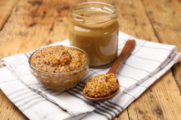 Different types of mustard on wooden table, closeup