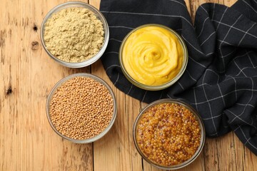 Different types of mustard on wooden table, flat lay